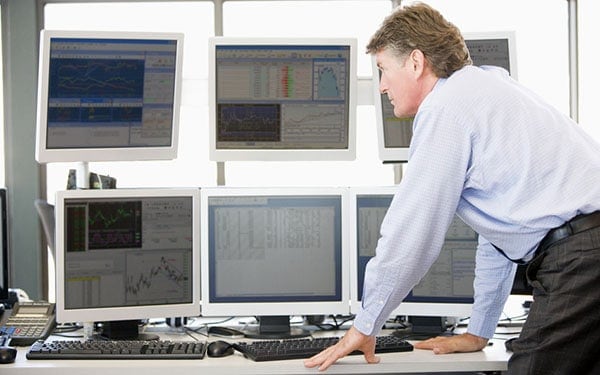 Stock Trader Examinando Monitores de Computador