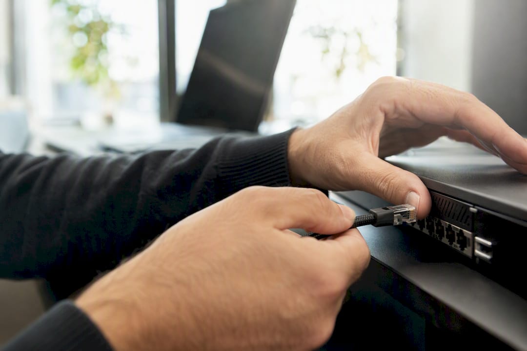 Hands adjusting network cable on trading hardware