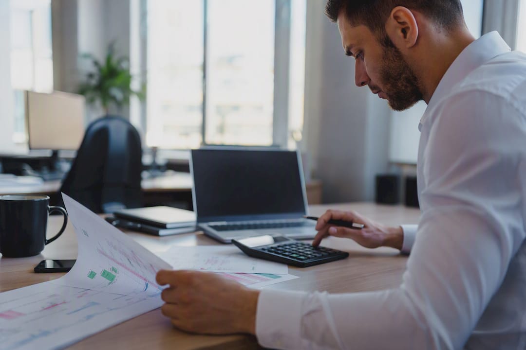 Trader calculating trade risk with calculator